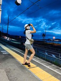 Woman standing on railroad track against sky. mask on fashion as the new normal