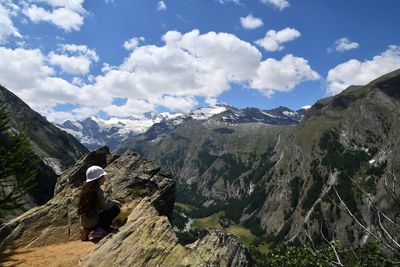 Full length of girl crouching while looking at mountain against sky