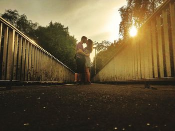 Couple standing by trees against sky