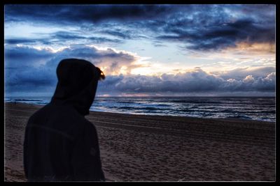 Rear view of silhouette man looking at sunset