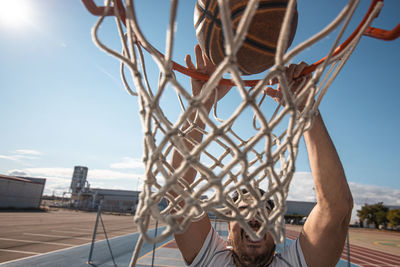 Close-up of man playing basketball against sky