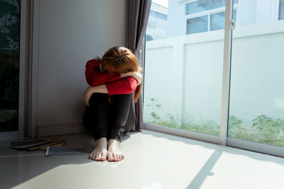 Rear view of woman in glass window at home