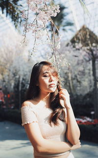 Young woman holding flower buds while standing at park