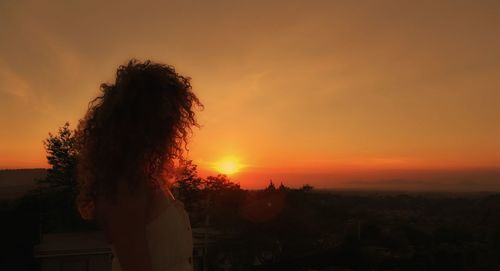 Silhouette woman against orange sky during sunset