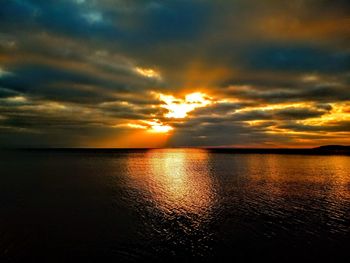 Scenic view of sea against dramatic sky during sunset