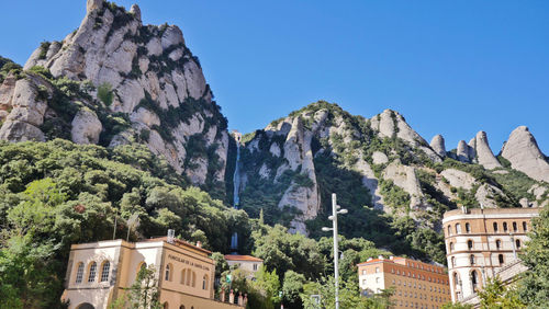 Low angle view of houses and mountains against clear sky