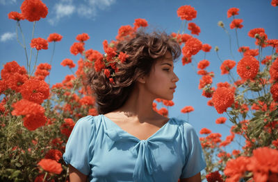 Portrait of young woman amidst yellow flowering plants on field