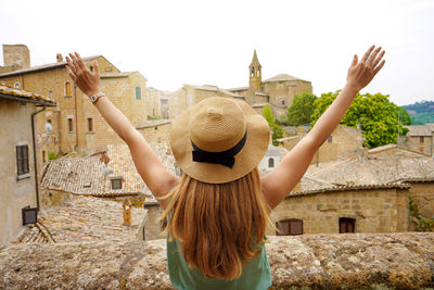 Happy young woman with arms up in orvieto city.  girl with arms outstretched raised on the town