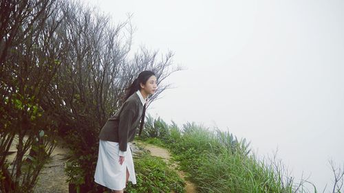 Side view of young woman walking against clear sky