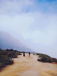 Rear view of people standing on mountain against sky