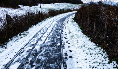 Snow covered road amidst trees during winter