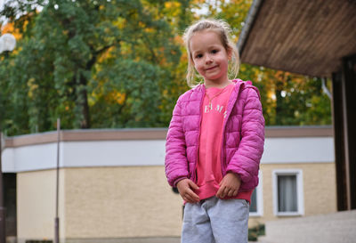 Portrait of young woman standing against trees