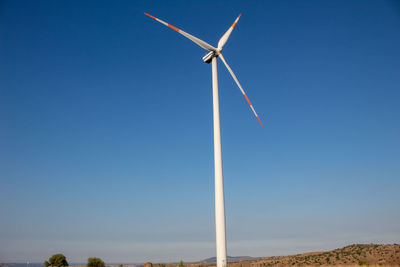 An entire wind turbine that starts from the ground with the sky as a background