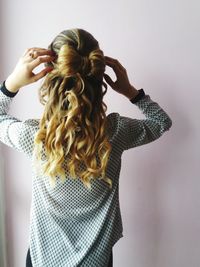 Rear view of woman with hairstyle standing against wall