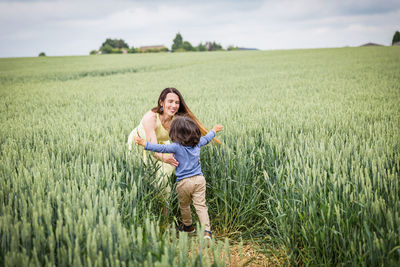 Mother and little handsome baby boy walking in field