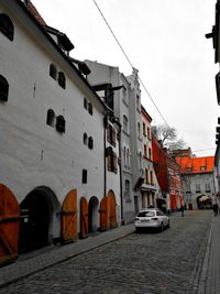 Cars on street by buildings against sky in city