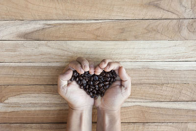 Cropped image of hand holding roasted coffee beans at table