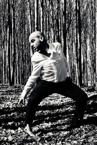 Portrait of man on tree trunk in forest