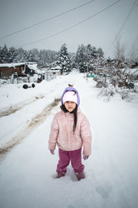 Portrait of girl standing on snow covered land