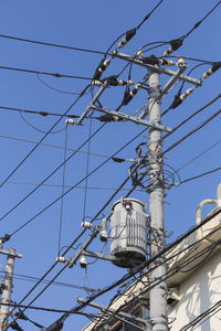 Low angle view of electricity pylon against clear blue sky