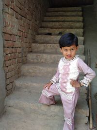 Portrait of cute girl standing against brick wall