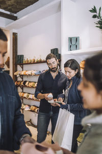 Female customer sharing smart phone with salesman at fashion boutique