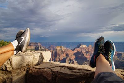 Low section of person on rock against sky