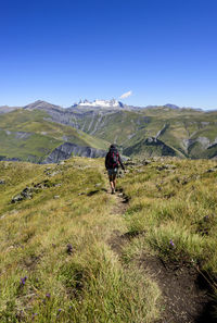 Woman adult trekking on a trail in the french alps with snowy peaks in the background,, france