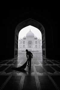 Silhouette man sweeping floor against taj mahal