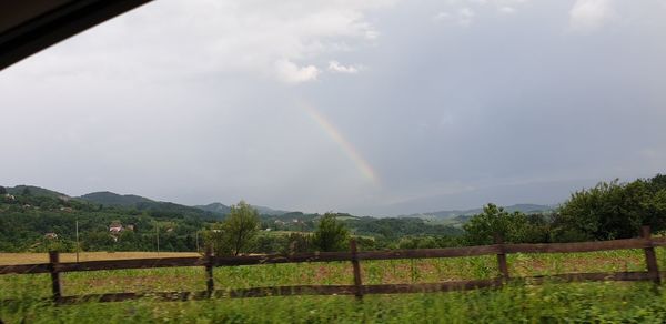 Scenic view of rainbow over field against sky