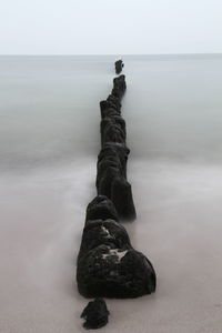 Rock on beach against sky