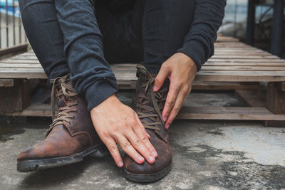 Low section of man cleaning shoes while sitting on palette