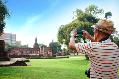 Man photographing with mobile phone in park