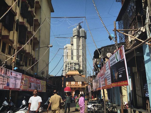 building exterior, architecture, built structure, city, men, person, lifestyles, city life, walking, large group of people, street, leisure activity, building, sky, day, rear view, low angle view, tower, outdoors