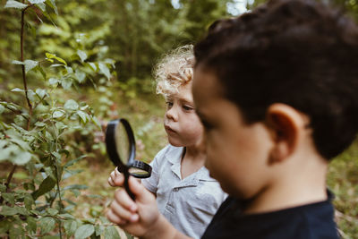 Curious boys looking at plants through magnifying glass