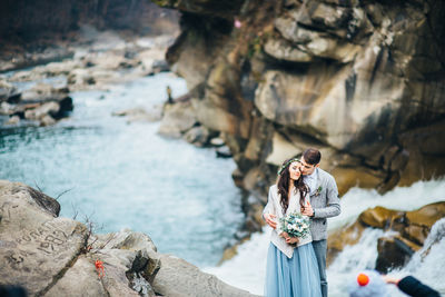 People standing on rock by water