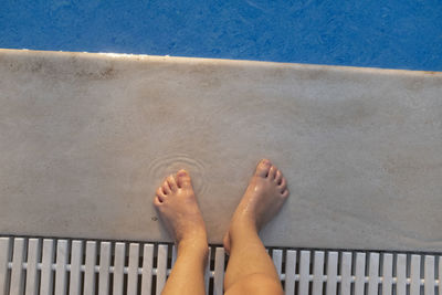 Low section of woman standing by swimming pool