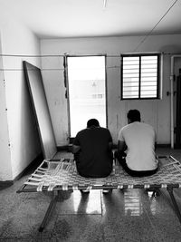 Rear view of people sitting on seat in corridor