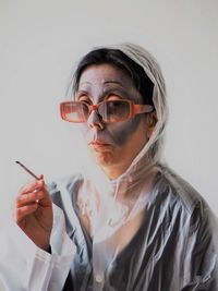 Portrait of young woman wearing eyeglasses against white background