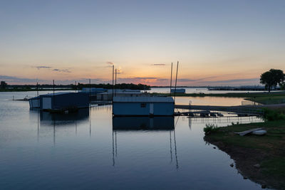 Boats moored in lake against sky during sunset