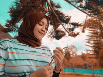 Portrait of woman wearing headscarf against trees during winter