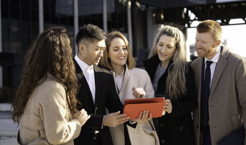 Portrait of smiling friends using digital tablet