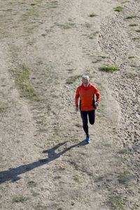 High angle view of senior man jogging on sand