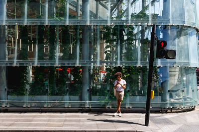 Full length of woman standing by window in city