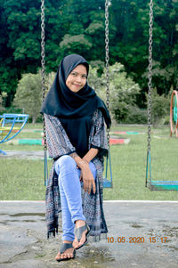 Full length of woman sitting on swing at playground