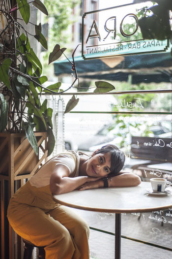 PORTRAIT OF YOUNG WOMAN SITTING ON PLANTS