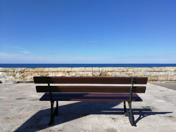 Empty chairs on beach against clear blue sky