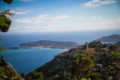 Aerial view of city by sea against sky