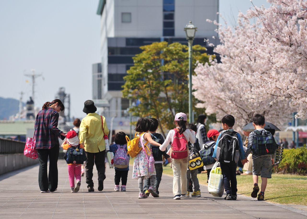 group of people, real people, building exterior, men, city, tree, architecture, women, built structure, medium group of people, day, group, plant, full length, walking, lifestyles, rear view, nature, adult, crowd, outdoors, cherry blossom, cherry tree