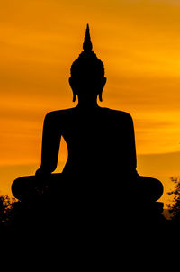 Silhouette of statue against orange sky